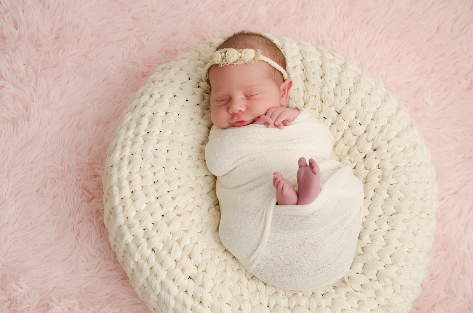 Bebê enrolado em manta clara durante ensaio newborn
