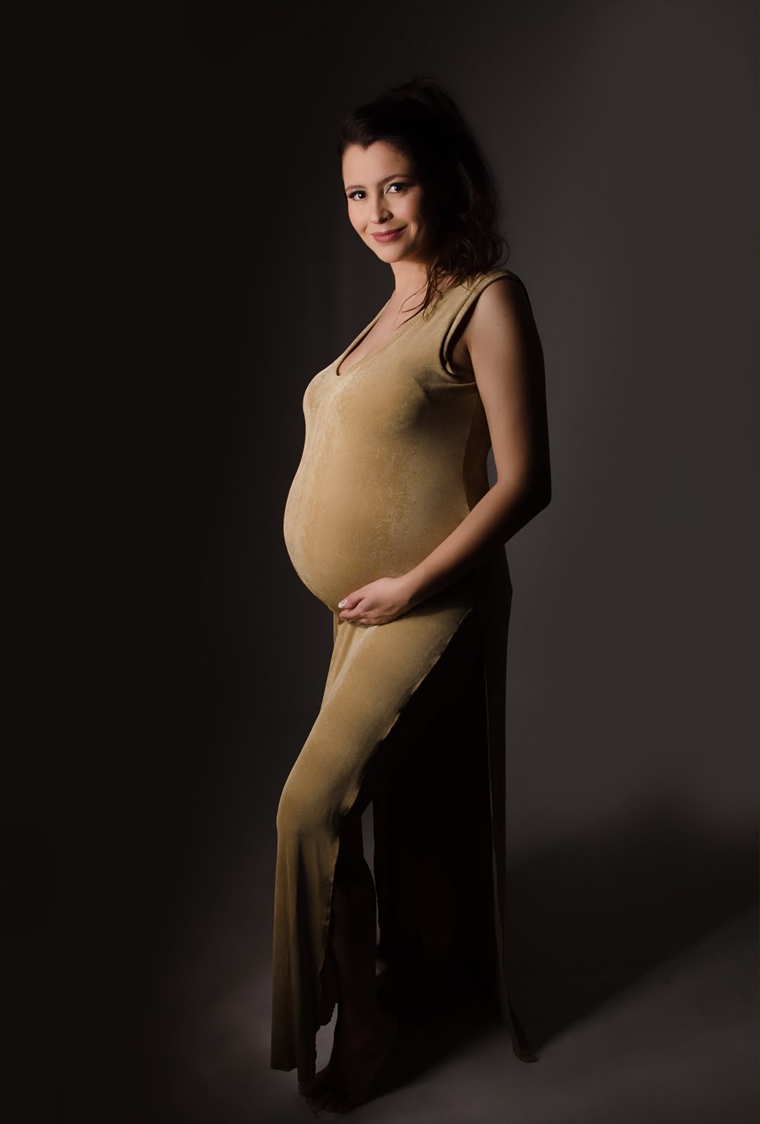 Retrato de gestante em vestido dourado com iluminação dramática